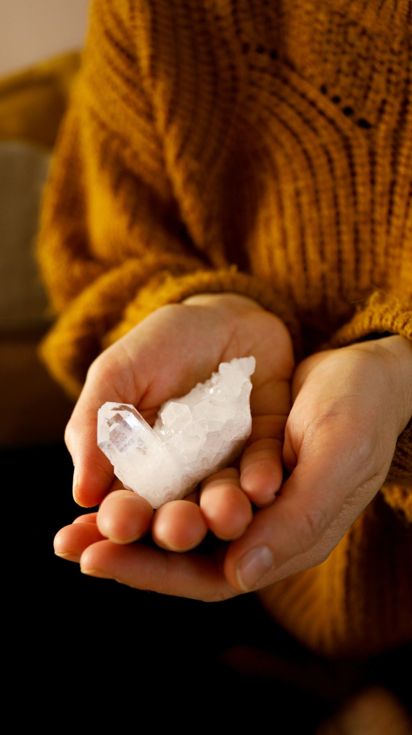 Close-up of hands holding a healing quartz crystal, representing alternative therapy and energy healing.